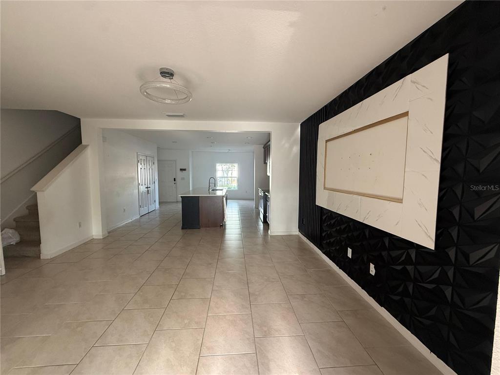 A living room with a black textured accent wall and a white marble-look TV mount — 1182 SAND TORCH CIRCLE, DAVENPORT, FL