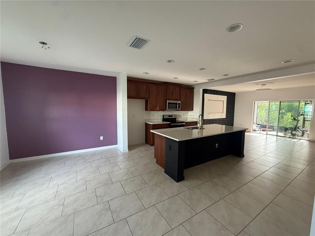 A kitchen with a large island, dark wood cabinets, and a purple accent wall — 1182 SAND TORCH CIRCLE, DAVENPORT, FL