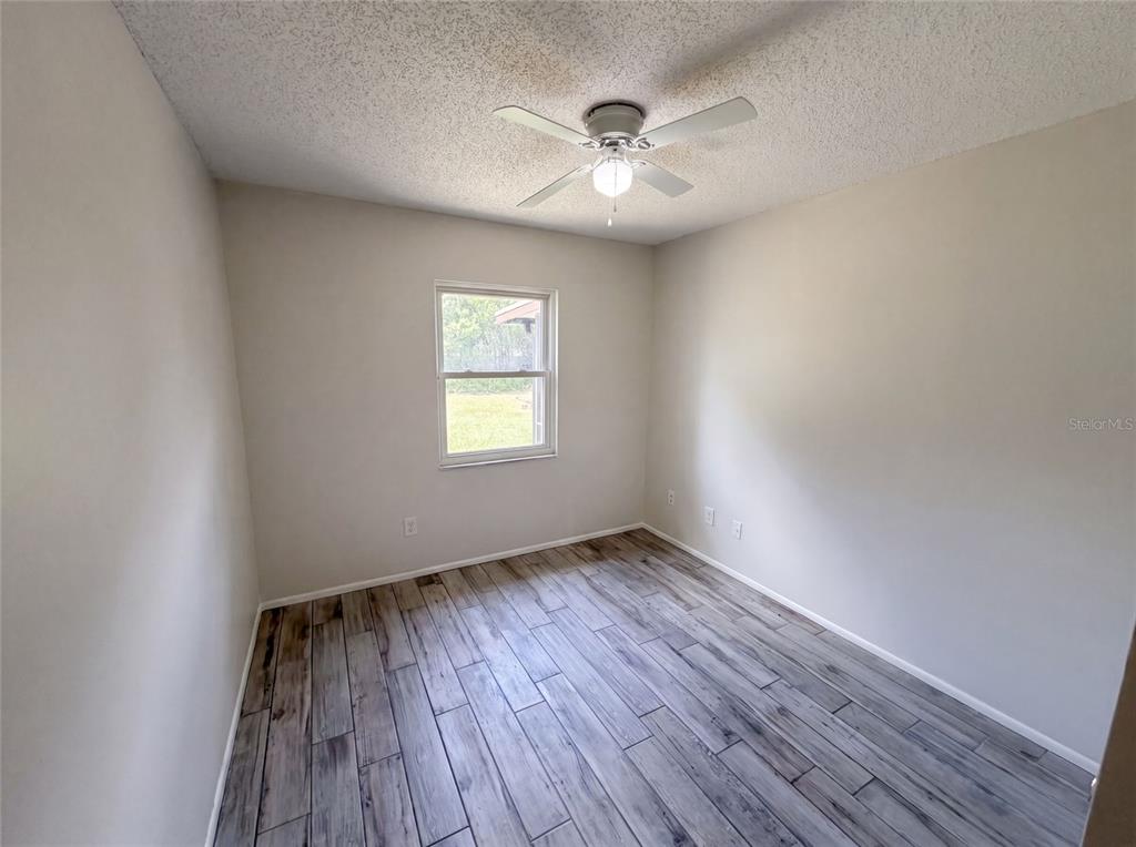 An empty bedroom features light-colored walls, a ceiling fan, and wood-look tile flooring — 2922 XAVIER COURT, ORLANDO, FL