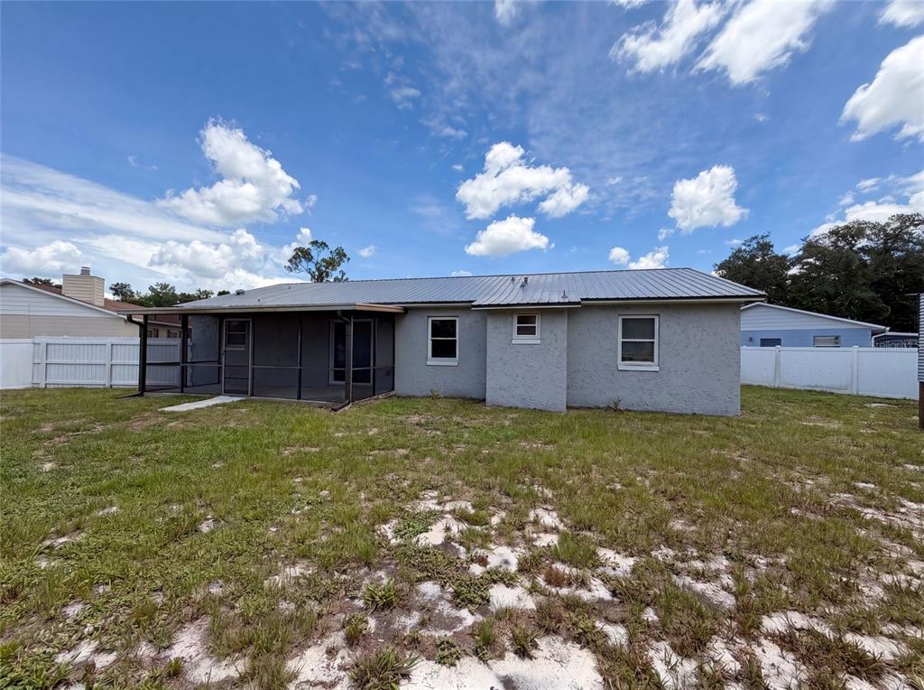 The rear exterior of a single-story house features a screened porch and a metal roof — 2922 XAVIER COURT, ORLANDO, FL