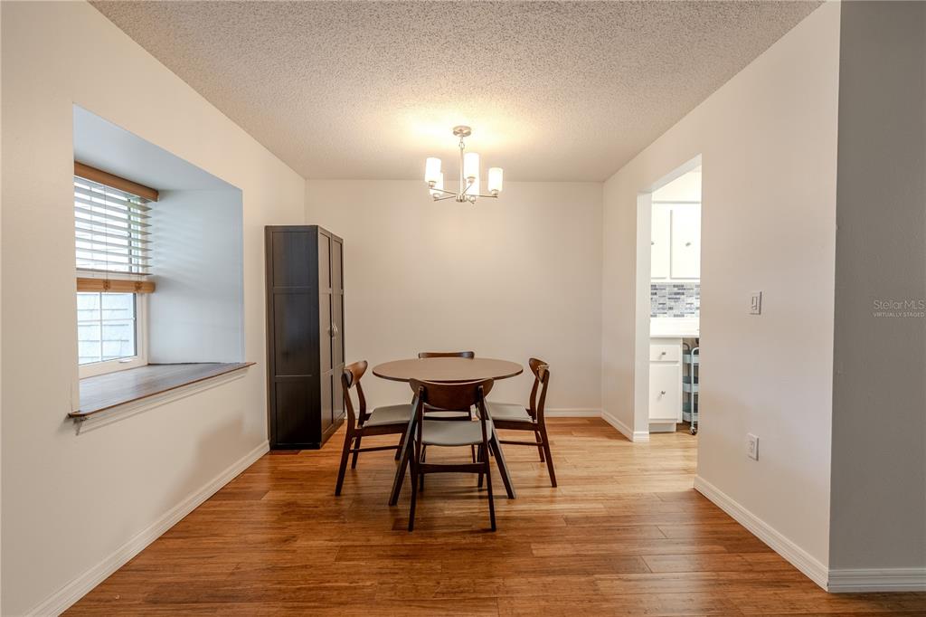 A dining room features wood flooring, a round table with three chairs, and a window nook — 1708 BELLEAIR FOREST DRIVE UNIT D, BELLEAIR, FL