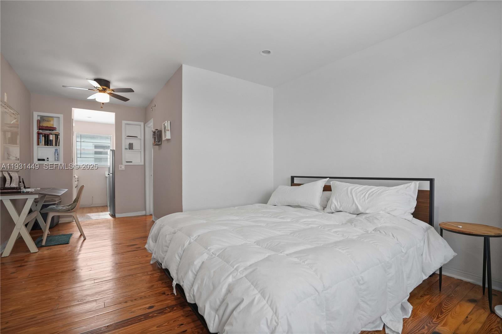 A bedroom features a bed with white bedding, hardwood floors, and an adjacent dining area — 200 76th St # 56, Miami Beach FL 33141, MIAMI BEACH, FL