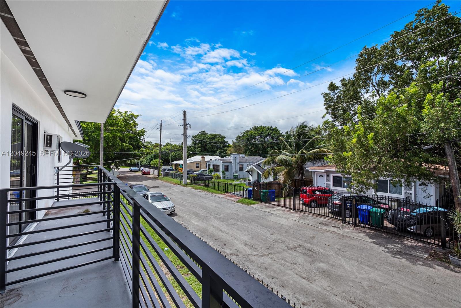 A view from a balcony overlooking a residential street with parked cars and houses — 131 NE 77th St, Miami FL 33138, MIAMI, FL