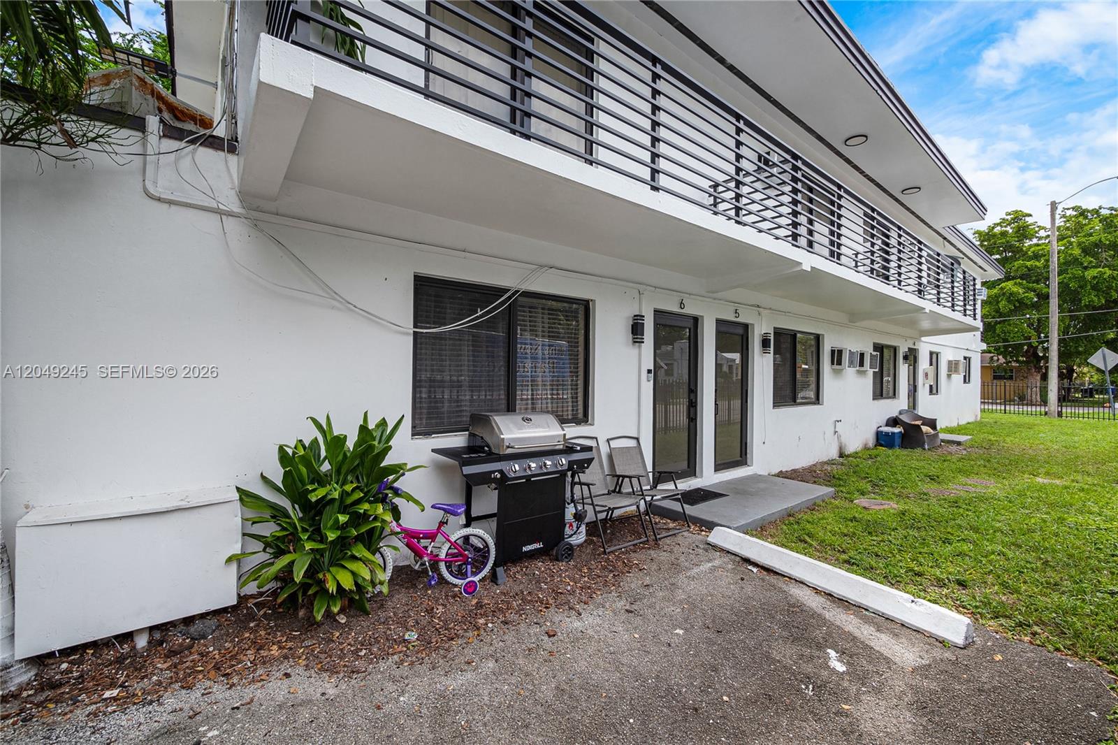 The exterior of a two-story apartment building features a ground-level patio with a grill — 131 NE 77th St, Miami FL 33138, MIAMI, FL