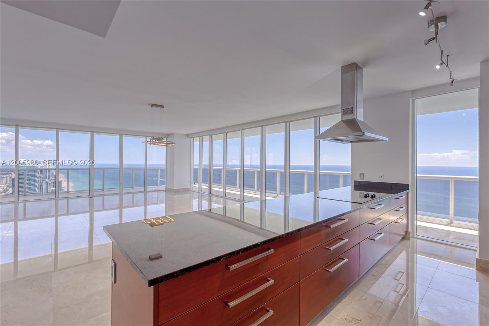 A modern kitchen island with wood cabinets and dark countertops overlooks the ocean through windows — 1830 S Ocean Dr # 4601, Hallandale Beach FL 33009, HALLANDALE BEACH, FL