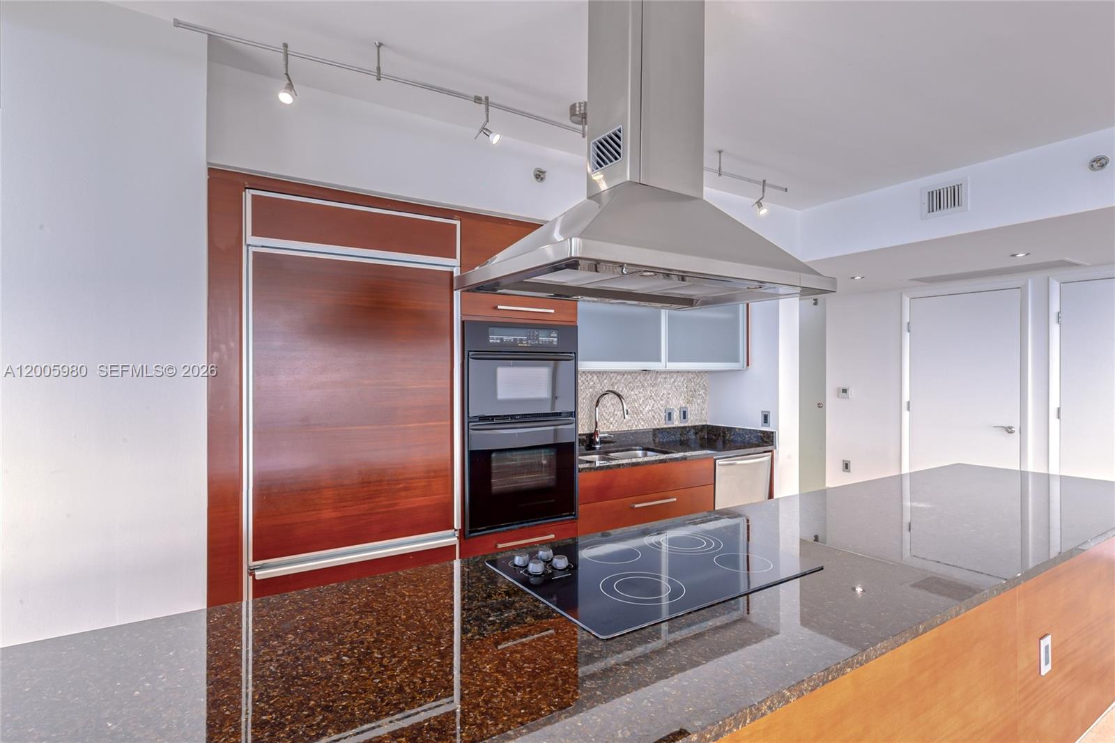 A modern kitchen features dark wood cabinetry, granite countertops, and a stainless steel range hood — 1830 S Ocean Dr # 4601, Hallandale Beach FL 33009, HALLANDALE BEACH, FL