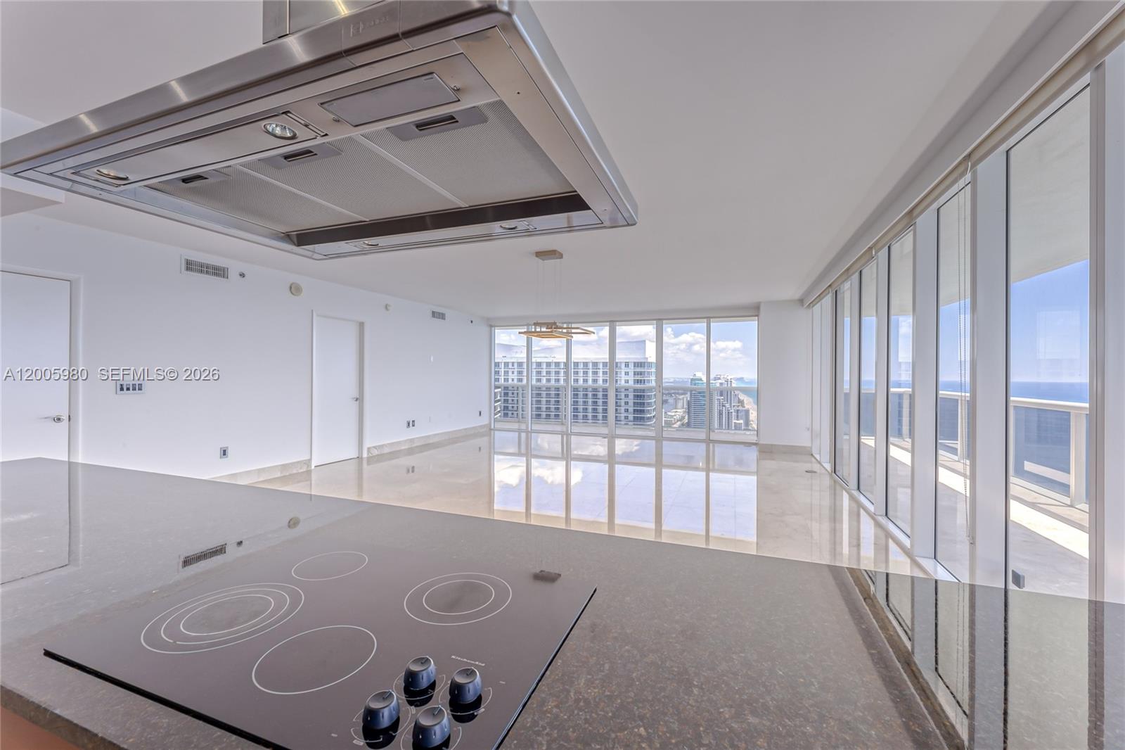 A kitchen island with a cooktop overlooks a bright, open living area with floor-to-ceiling windows — 1830 S Ocean Dr # 4601, Hallandale Beach FL 33009, HALLANDALE BEACH, FL