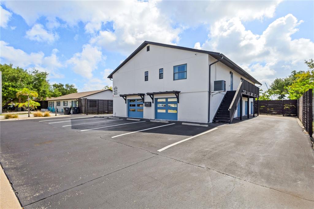 A two-story white building with blue garage doors and an exterior staircase sits on asphalt — 4219 60TH STREET COURT W, BRADENTON, FL
