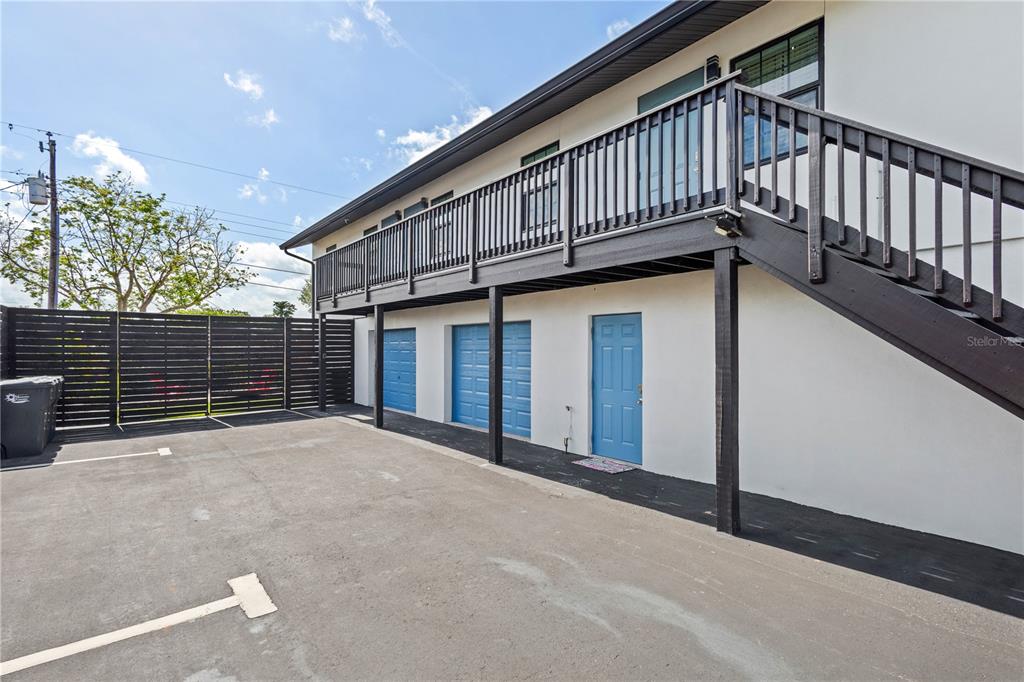 An exterior view of a building with a parking area, blue garage doors, and stairs — 4219 60TH STREET COURT W, BRADENTON, FL