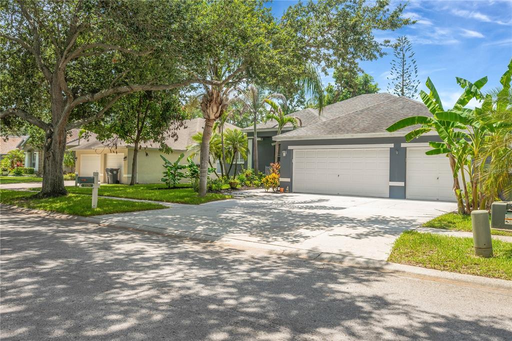 A gray house with a two-car garage and a concrete driveway sits on a street — 1128 LUMSDEN TRACE CIRCLE, VALRICO, FL