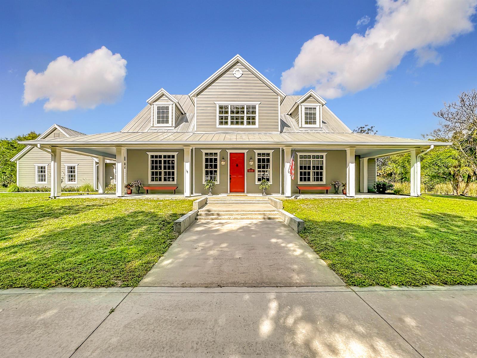 A two-story house with a metal roof, gray siding, and a bright red front door — 2135 55th Avenue SW, Vero Beach FL 32968, VERO BEACH, FL