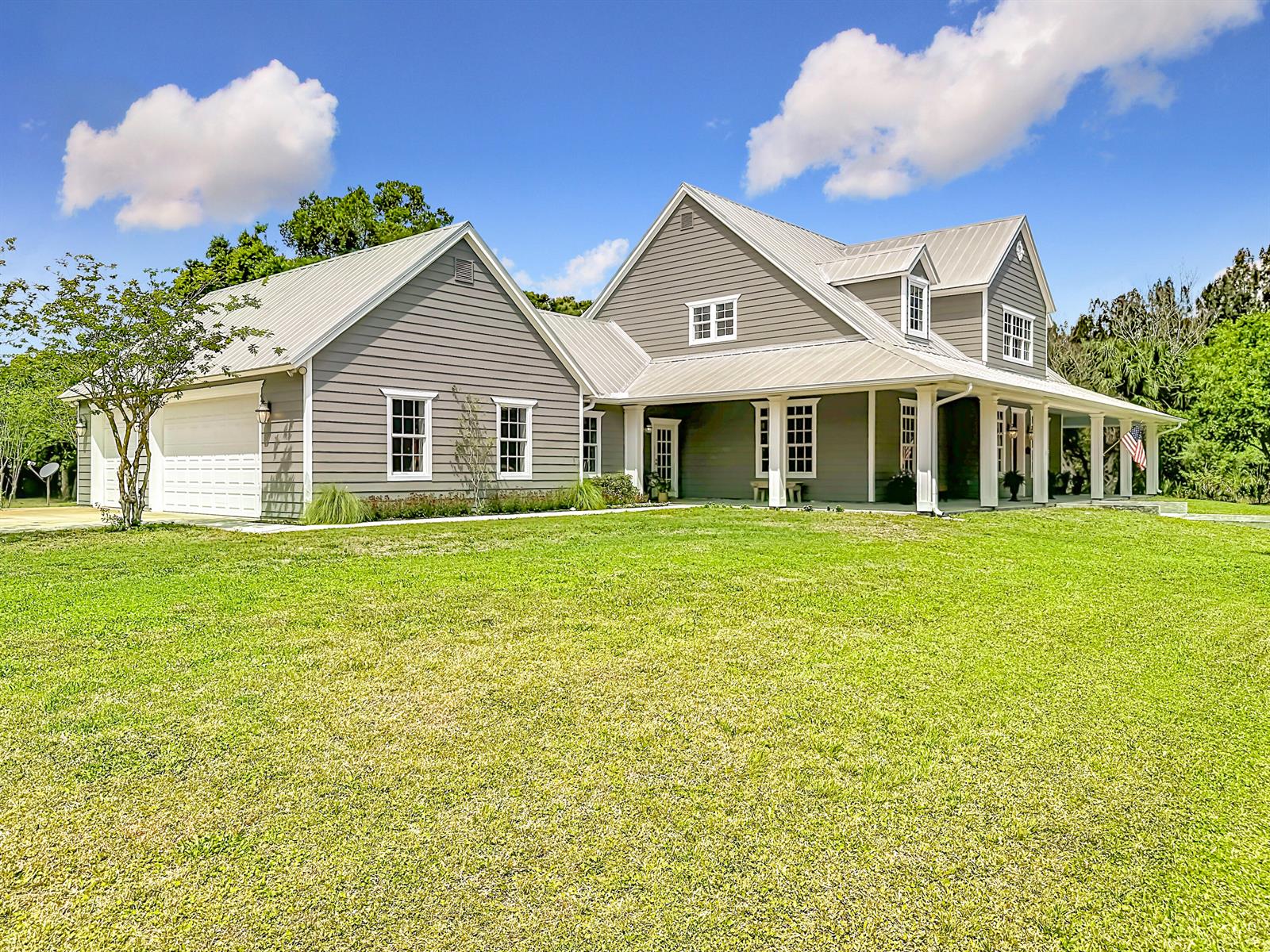 A two-story gray house with a metal roof, white trim, and a large front lawn — 2135 55th Avenue SW, Vero Beach FL 32968, VERO BEACH, FL