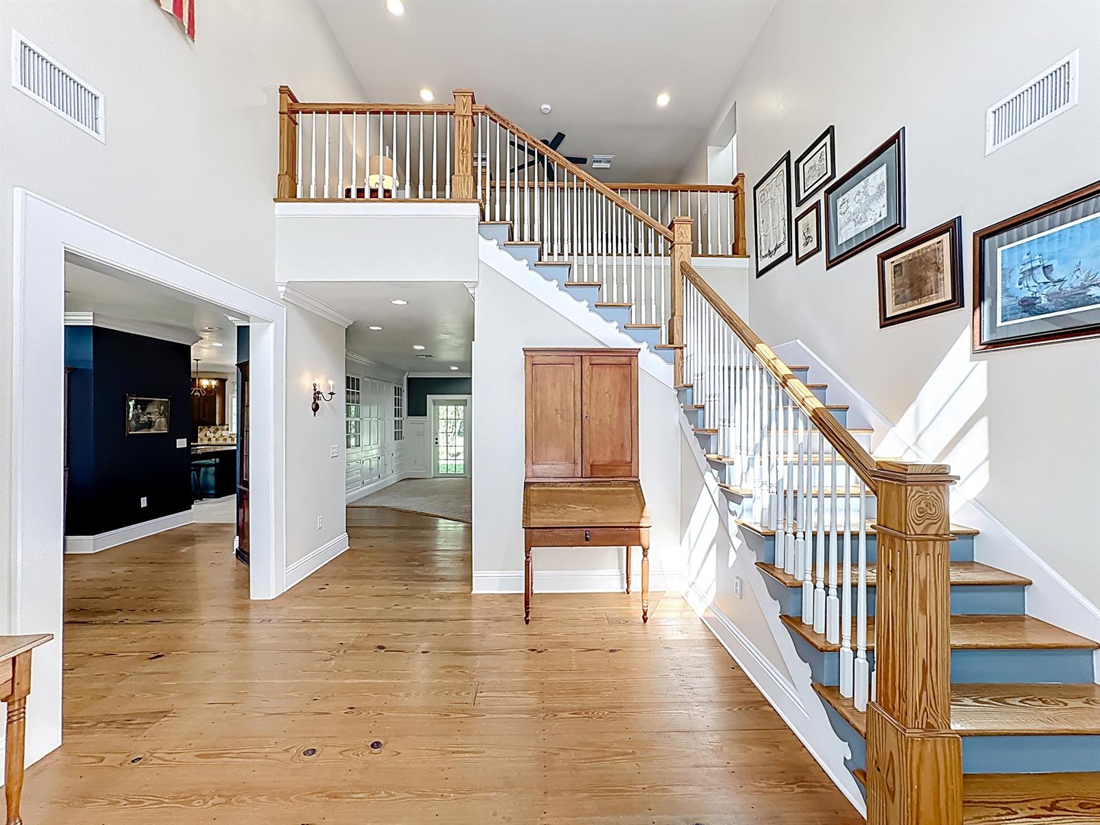 A foyer features hardwood floors, a wooden secretary desk, and a staircase with white railings — 2135 55th Avenue SW, Vero Beach FL 32968, VERO BEACH, FL