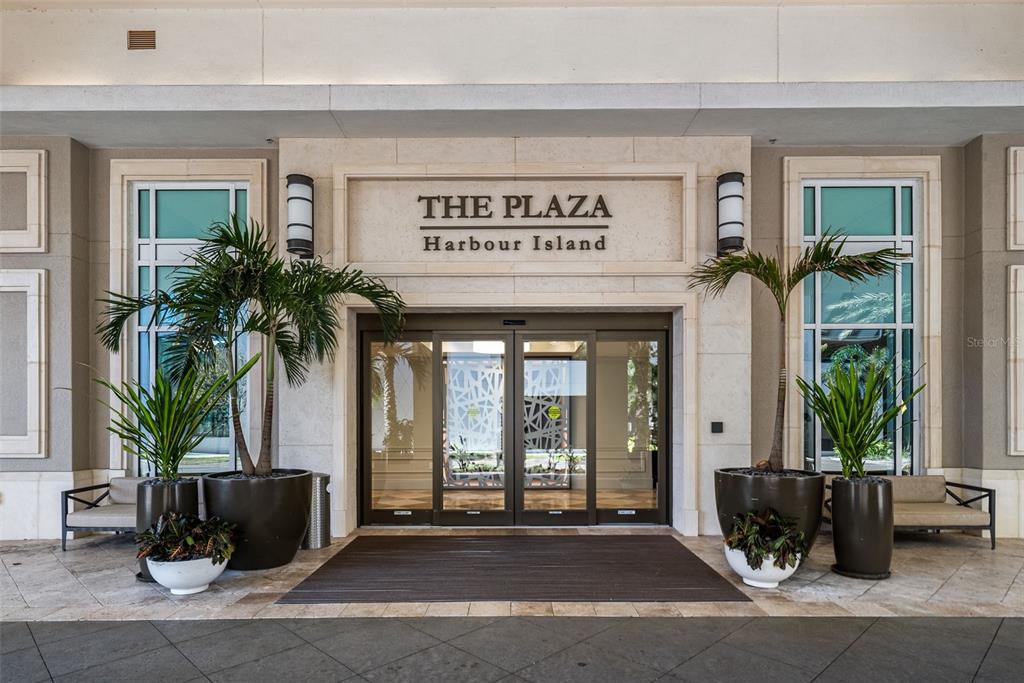 The entrance to The Plaza Harbour Island features glass doors flanked by potted palm trees — 450 KNIGHTS RUN AVENUE UNIT 405, TAMPA, FL