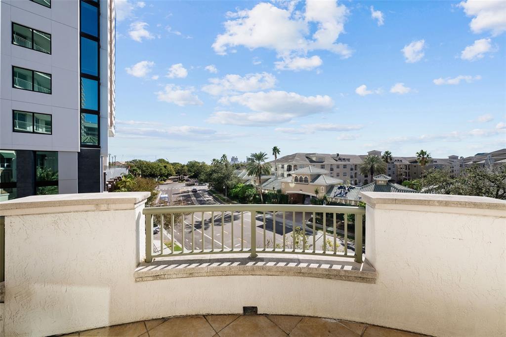A balcony with a curved stone wall and metal railing overlooks a street and buildings — 450 KNIGHTS RUN AVENUE UNIT 405, TAMPA, FL
