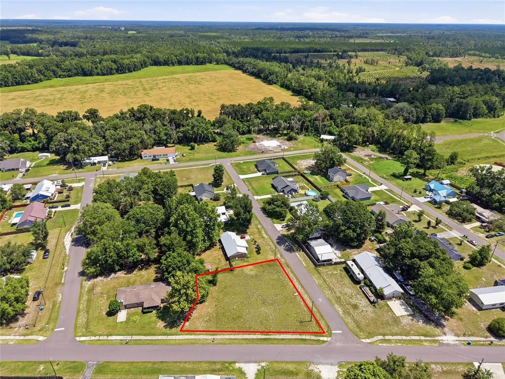 An aerial view shows a vacant, grass-covered residential lot outlined in red within a neighborhood — CHERRY STREET, BROOKER, FL
