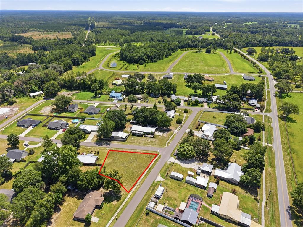 An aerial view shows a vacant, triangular-shaped residential lot outlined in red — CHERRY STREET, BROOKER, FL