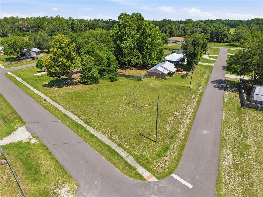 An aerial view shows a vacant, grassy corner lot bordered by two paved residential streets — CHERRY STREET, BROOKER, FL