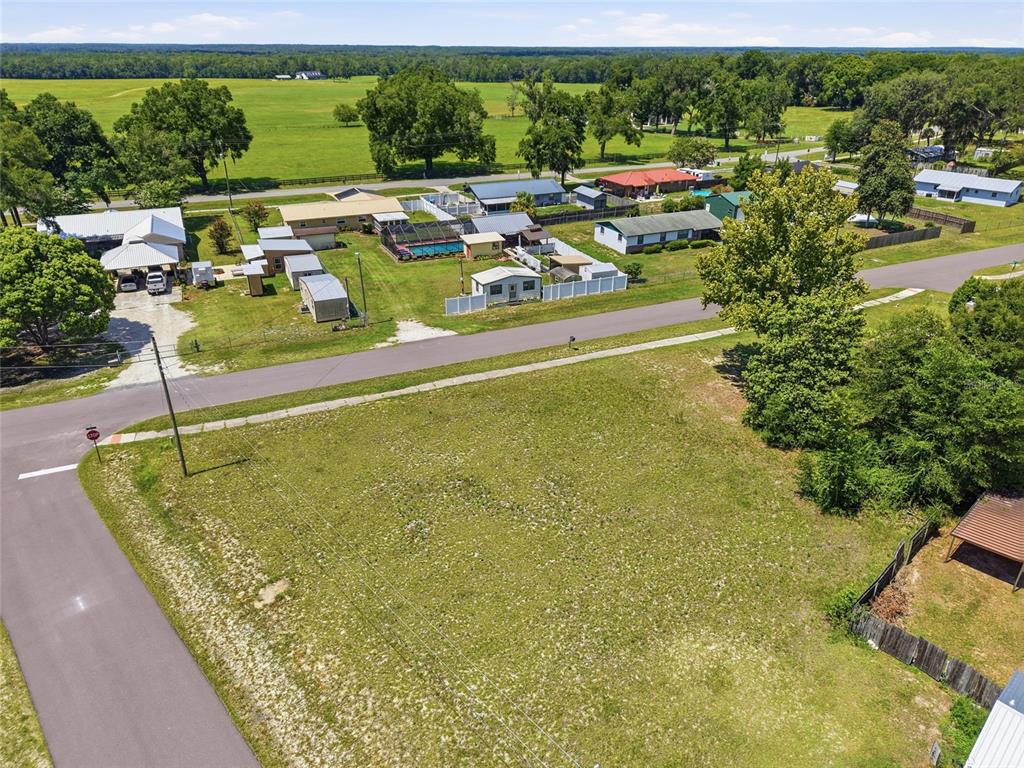 An aerial view shows a vacant grassy lot adjacent to a residential street and neighborhood — CHERRY STREET, BROOKER, FL