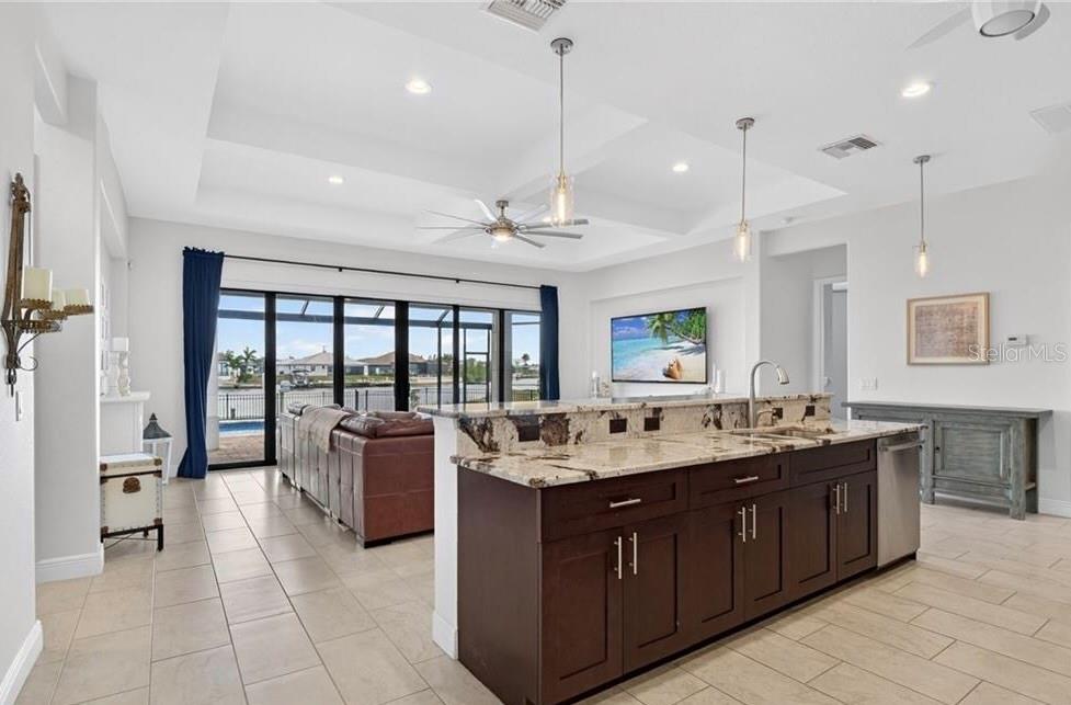 A kitchen island with granite countertops overlooks a living area with large sliding glass doors — 3331 NW 46TH AVENUE, CAPE CORAL, FL