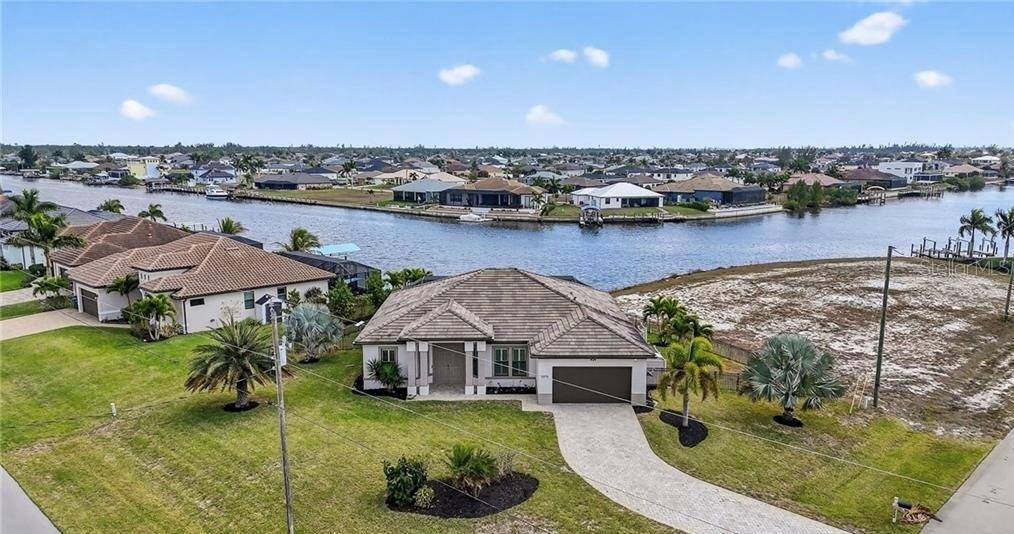 An aerial view shows a single-story house with a tiled roof near a canal — 3331 NW 46TH AVENUE, CAPE CORAL, FL