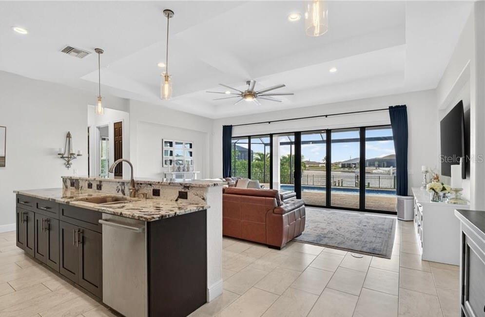 A kitchen with dark cabinets and granite countertops overlooks a living area with pool views — 3331 NW 46TH AVENUE, CAPE CORAL, FL