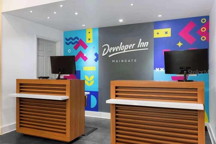 A hotel reception area features two wooden desks with computers against a colorful graphic wall — 2930 POLYNESIAN ISLE BOULEVARD UNIT 245, KISSIMMEE, FL