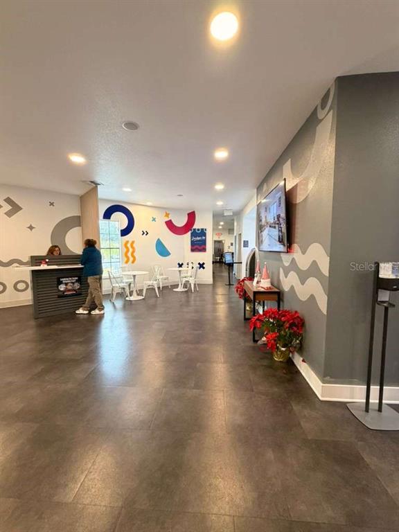 A brightly lit lobby features a reception desk, seating area, and colorful wall murals — 2930 POLYNESIAN ISLE BOULEVARD UNIT 245, KISSIMMEE, FL