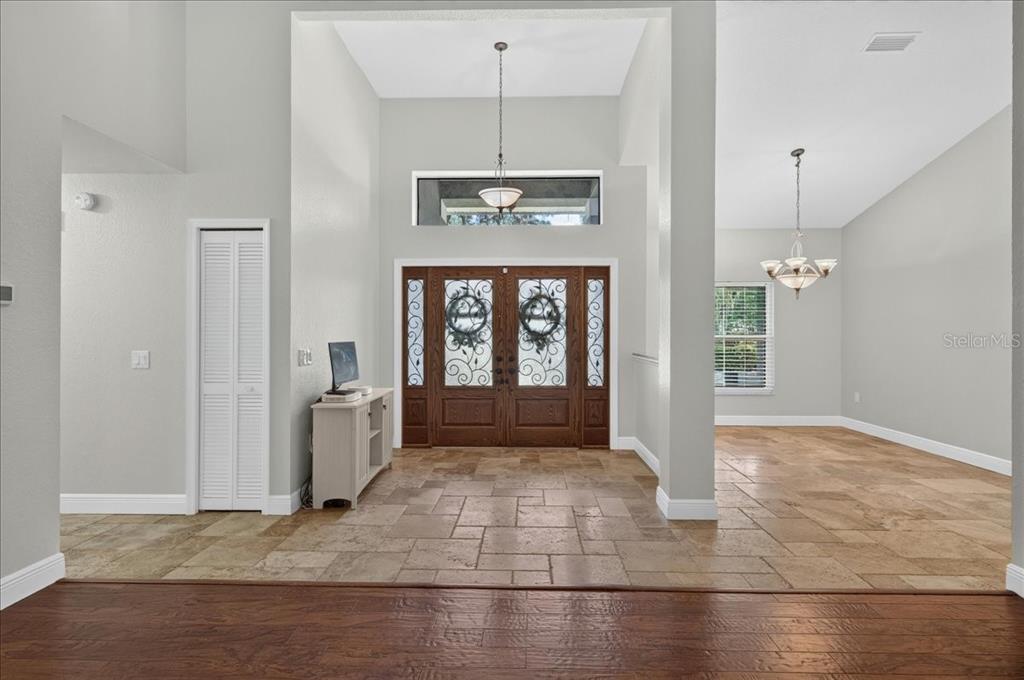An entryway with tile flooring, a double front door, and a chandelier under a high ceiling — 16754 CROSSBILL COURT, SPRING HILL, FL