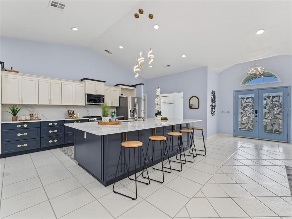 A modern kitchen features a large dark blue island with bar stools and white cabinets — 8342 DANBURY LANE, HUDSON, FL