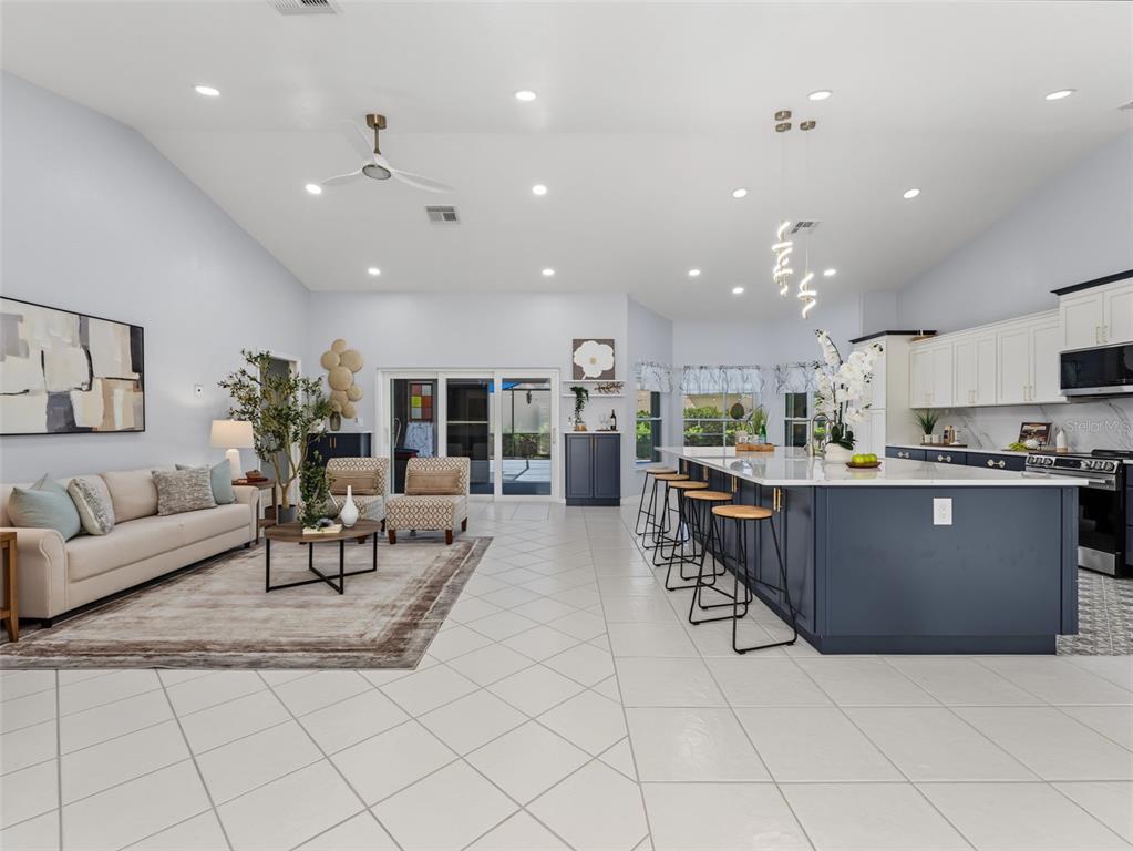 An open-concept living room and kitchen featuring a large island, tile floors, and vaulted ceilings — 8342 DANBURY LANE, HUDSON, FL