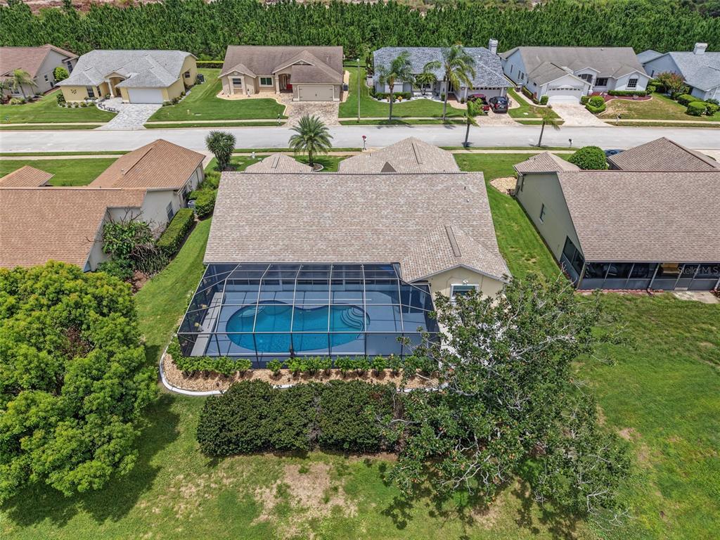 An aerial view of a suburban house featuring a screened-in pool and a large backyard — 8342 DANBURY LANE, HUDSON, FL