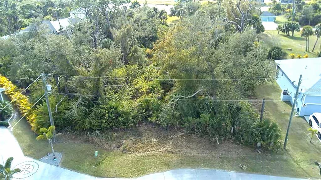 An aerial view shows a vacant, wooded residential lot situated between two existing houses — 102 SUNNY WAY, ROTONDA WEST, FL