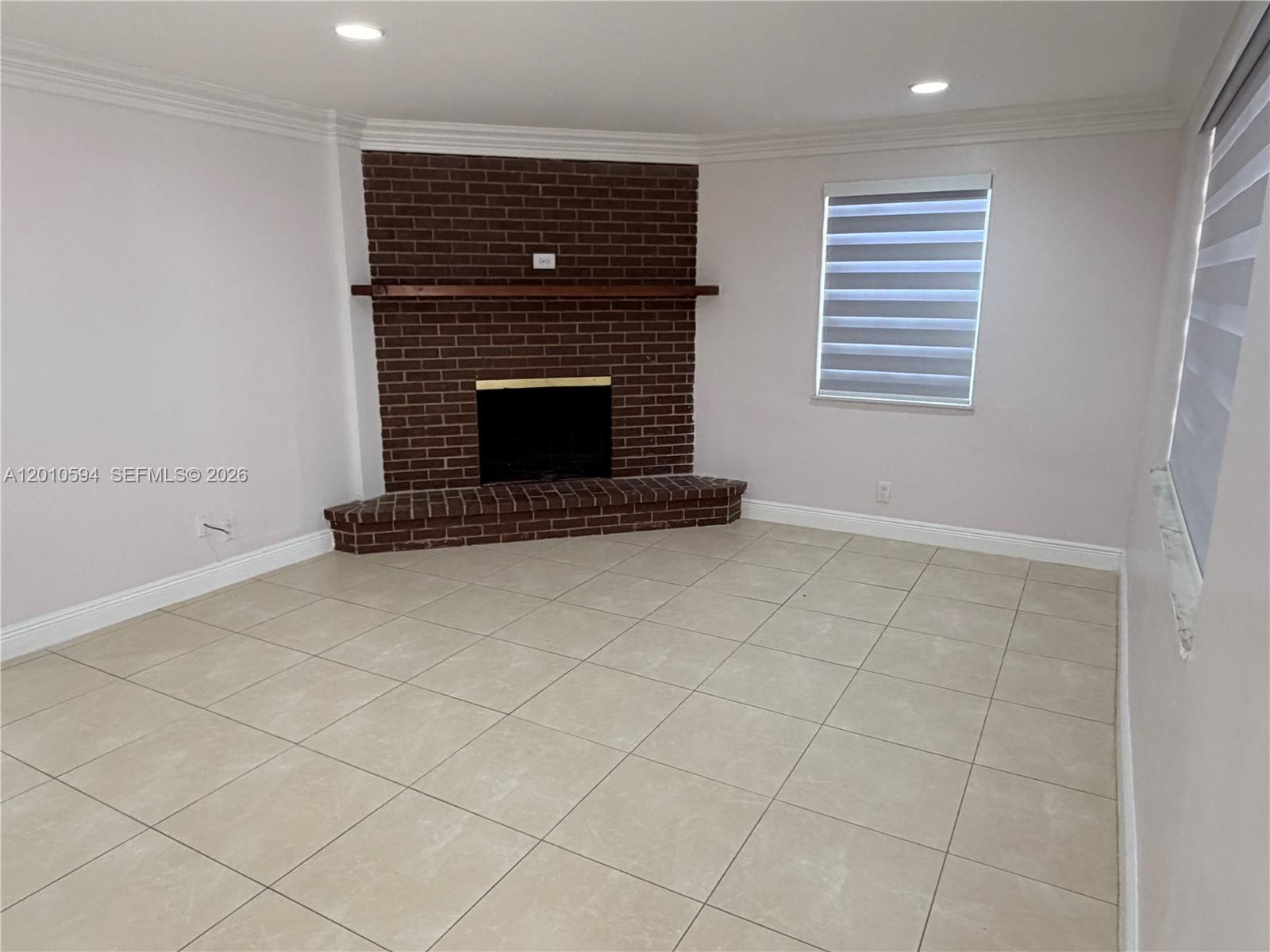 A room with beige tile flooring, light walls, and a corner brick fireplace — 3011 N 74th Ave, Hollywood FL 33024, HOLLYWOOD, FL