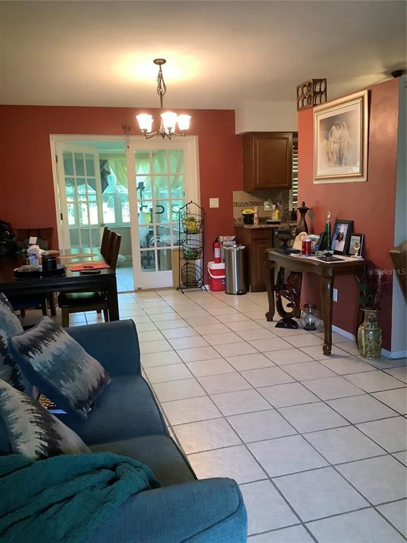 A living room with tile floors, a dining area, and a red accent wall — 819 62ND AVENUE S, ST PETERSBURG, FL
