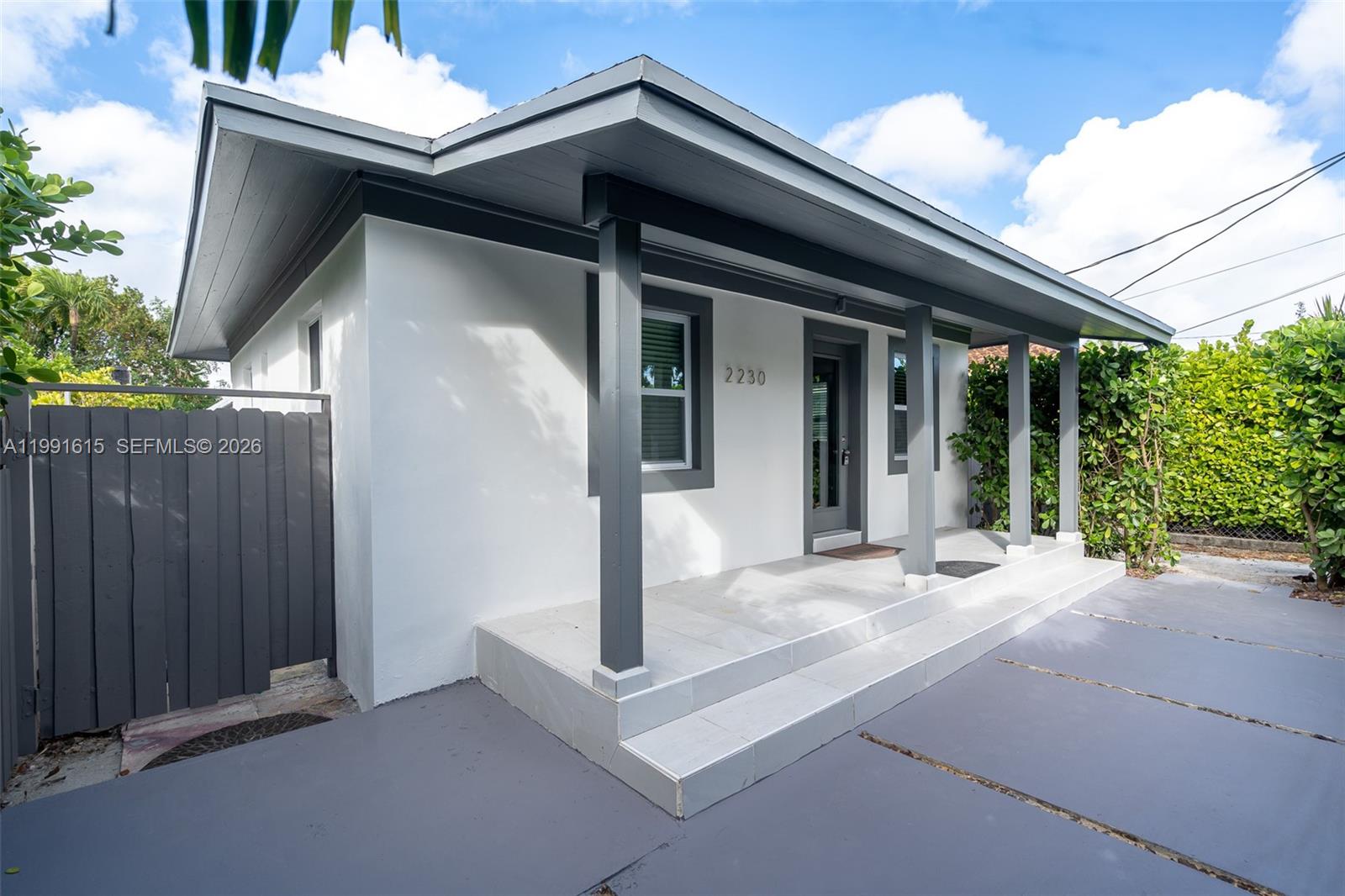 A white house with a gray porch, dark trim, and a fenced side yard — 2230 SW 60th Ct, Miami FL 33155, MIAMI, FL