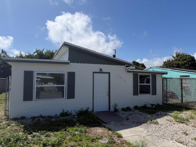 A single-story house with a white stucco exterior, dark shutters, and a gravel front yard — 1214 Highview Road, Lake Worth FL 33462, LAKE WORTH, FL