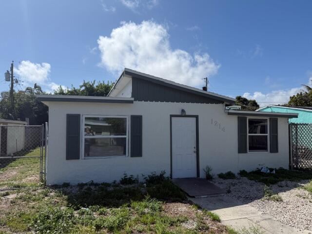 A single-story house with a white stucco exterior, dark shutters, and a slanted roof — 1214 Highview Road, Lake Worth FL 33462, LAKE WORTH, FL