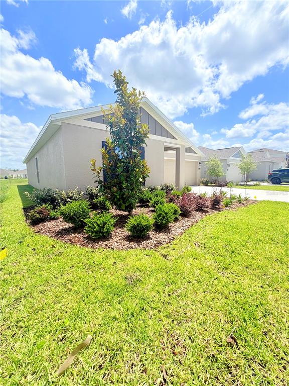 A single-story house with a beige exterior, a small front garden, and a blue sky — 5135 MAGNOLIA DRIVE, DAYTONA BEACH, FL