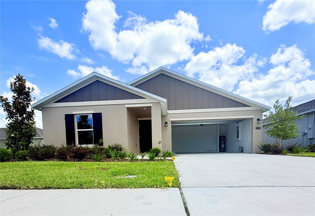 A single-story house with a beige stucco exterior, dark shutters, and an attached two-car garage — 5135 MAGNOLIA DRIVE, DAYTONA BEACH, FL