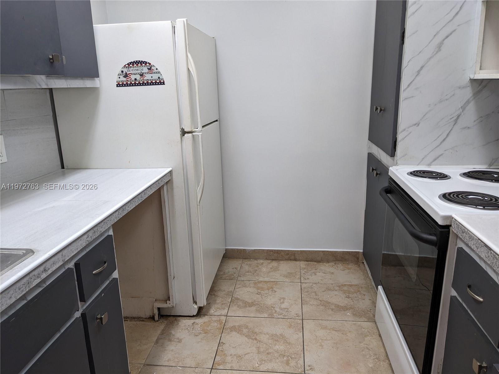 A kitchen features a white refrigerator, a white electric stove, and gray cabinets — 300 NE 191st St # 211, Miami FL 33179, MIAMI, FL