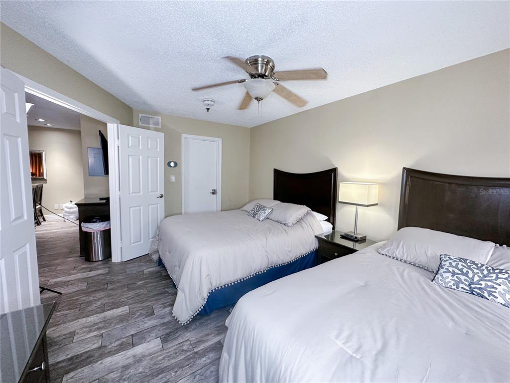 A bedroom features two beds, wood-look tile flooring, and a ceiling fan — 3100 PARKWAY BOULEVARD UNIT 110, KISSIMMEE, FL