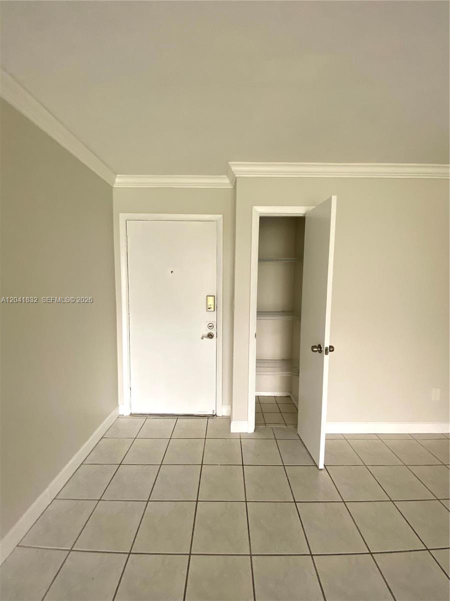 A room with light-colored tile flooring, a white entry door, and an open closet — 9280 FONTAINEBLEAU BL # 103, Miami FL 33172, MIAMI, FL