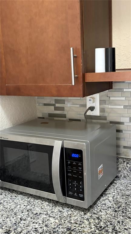 A kitchen features dark wood cabinets, granite countertops, a microwave, and a portable induction cooktop — 389 NOLANE LANE, POLK CITY, FL