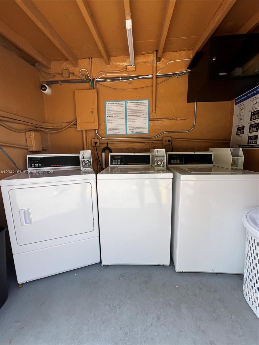A laundry room features three white appliances, exposed ceiling beams, and instructional wall signs — 7155 W 14th Ct # 10, Hialeah FL 33014, HIALEAH, FL