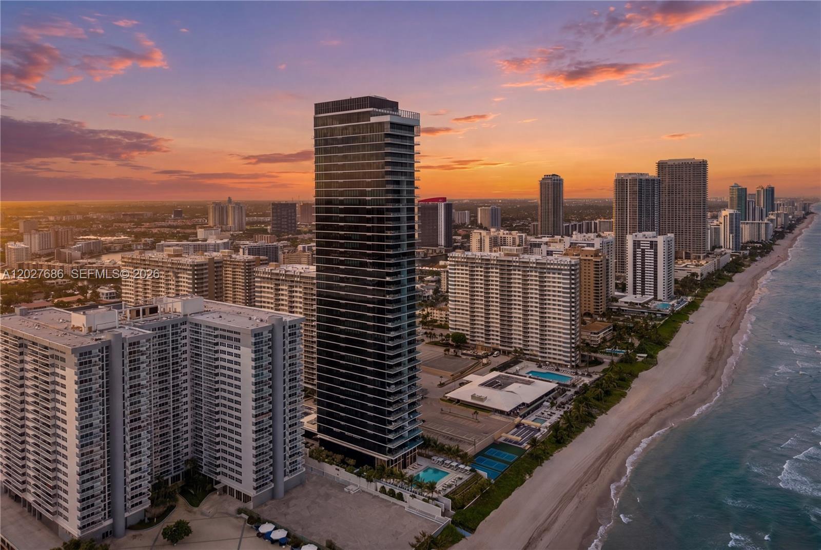 An aerial view shows a tall, dark glass skyscraper situated on a sandy beach — 2000 S Ocean Dr # 33A, Hallandale Beach FL 33009, HALLANDALE BEACH, FL