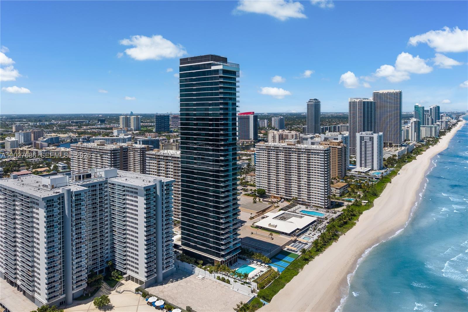 An aerial view shows a tall, dark glass residential tower surrounded by other high-rise buildings — 2000 S Ocean Dr # 33A, Hallandale Beach FL 33009, HALLANDALE BEACH, FL
