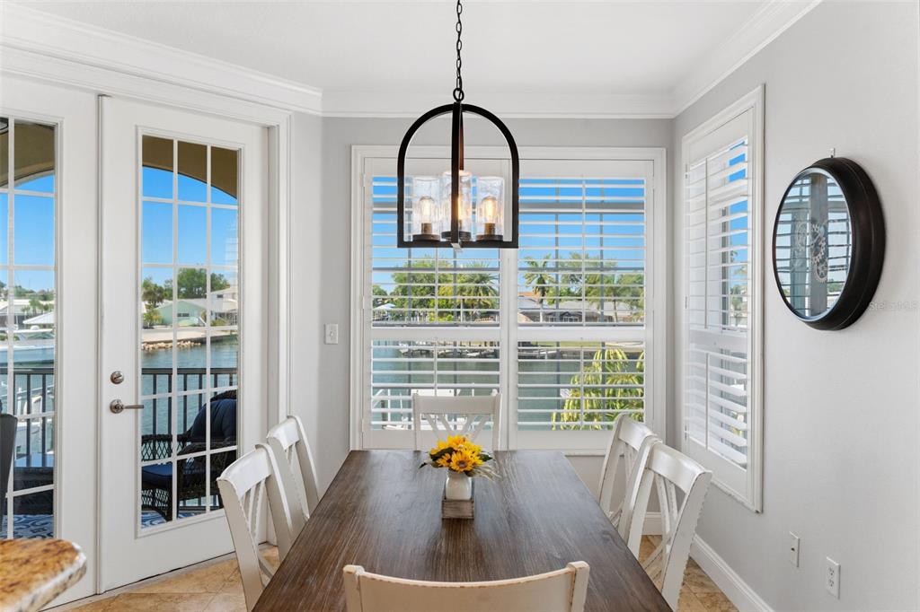 A dining area features a wooden table, white chairs, a pendant light, and waterfront views — 6420 SUNSET BAY CIRCLE, APOLLO BEACH, FL