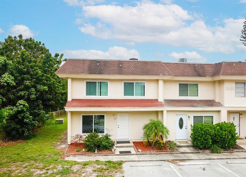 A two-story townhouse exterior features beige siding, a brown shingled roof, and a parking lot — 309 AMHERST AVENUE UNIT 51, SARASOTA, FL