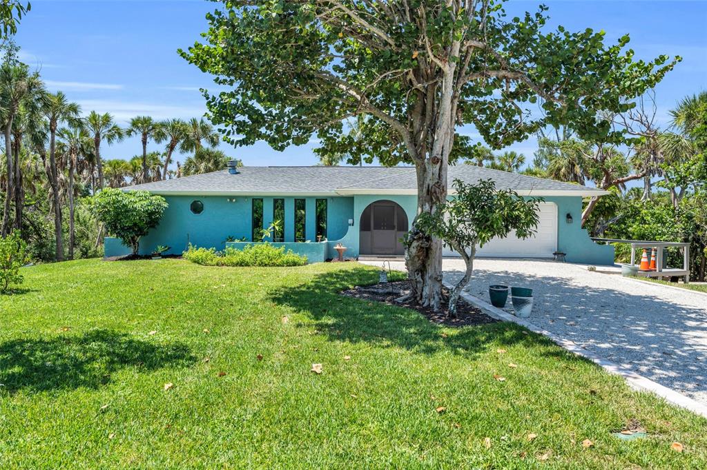A single-story turquoise house with a gravel driveway and a large tree in the yard — 4636 BUCK KEY ROAD, SANIBEL, FL